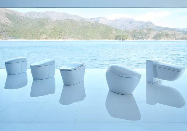 Five white toilets with mountain lake view.