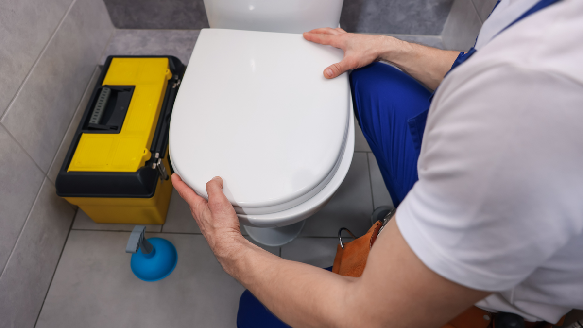 man installing a toilet seat in bathroom