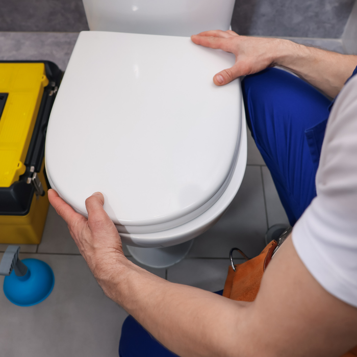 man installing a toilet seat in bathroom